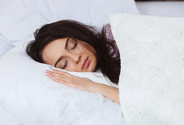Kız evde beyaz bir yatakta uyuyor. Yatakta evde, üstten görünüm beyaz keten üzerinde pijama içinde uyuyan genç kadın.