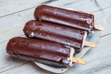 Çikolatalı dondurma bir mavi ahşap arka plan üzerine çıkar. Paslı bir arka plan üzerine çikolatalı dondurma. Eskimo dondurma Stick.