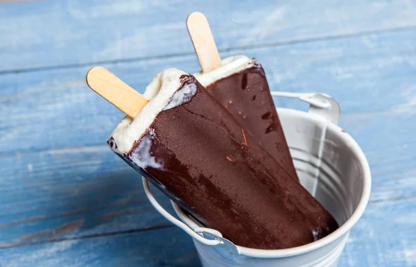 Chocolate ice cream pops on a blue wooden background. Chocolate ice cream on a rusty background. Eskimo ice cream on stick.