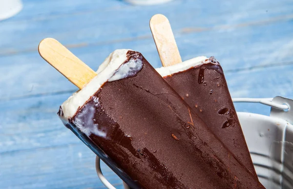 Chocolate ice cream pops on a blue wooden background. Chocolate ice cream on a rusty background. Eskimo ice cream on stick.