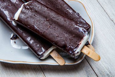 Çikolatalı dondurma bir mavi ahşap arka plan üzerine çıkar. Paslı bir arka plan üzerine çikolatalı dondurma. Eskimo dondurma Stick.