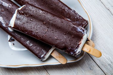 Çikolatalı dondurma bir mavi ahşap arka plan üzerine çıkar. Paslı bir arka plan üzerine çikolatalı dondurma. Eskimo dondurma Stick.