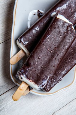 Çikolatalı dondurma bir mavi ahşap arka plan üzerine çıkar. Paslı bir arka plan üzerine çikolatalı dondurma. Eskimo dondurma Stick.