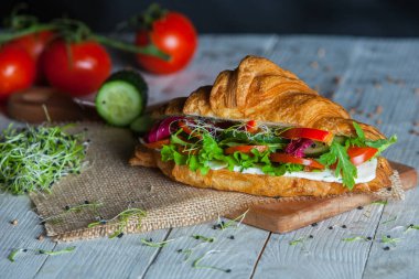 Kruvasan sandviç üzerinde ahşap kurulunda görev yapmaktadır. Kruvasan yumurta, eritilmiş peynir, maydanoz, tavuk jambon, füme somon ile