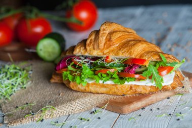 Kruvasan sandviç üzerinde ahşap kurulunda görev yapmaktadır. Kruvasan yumurta, eritilmiş peynir, maydanoz, tavuk jambon, füme somon ile