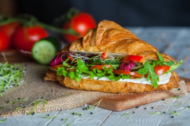 Kruvasan sandviç üzerinde ahşap kurulunda görev yapmaktadır. Kruvasan yumurta, eritilmiş peynir, maydanoz, tavuk jambon, füme somon ile