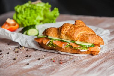 Kruvasan sandviç somon ve yeşil maydanoz ile. Kruvasan ile ahşap kesme tahtası üzerinde kırmızı balık. Sağlıklı kahvaltı. Meze. Başlangıç yemek