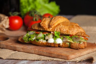 Kruvasan sandviç üzerinde ahşap kurulunda görev yapmaktadır. Kruvasan yumurta, eritilmiş peynir, maydanoz, tavuk jambon, füme somon ile