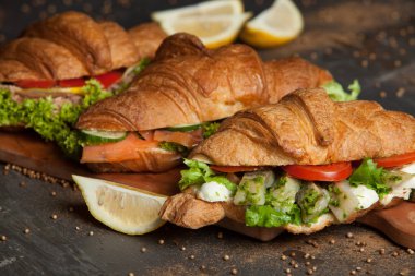 Kruvasan sandviç üzerinde ahşap kurulunda görev yapmaktadır. Kruvasan yumurta, eritilmiş peynir, maydanoz, tavuk jambon, füme somon ile