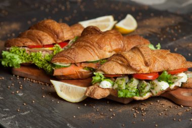 Kruvasan sandviç üzerinde ahşap kurulunda görev yapmaktadır. Kruvasan yumurta, eritilmiş peynir, maydanoz, tavuk jambon, füme somon ile