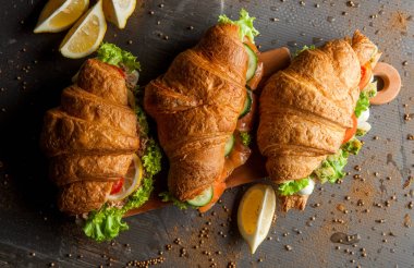 Kruvasan sandviç üzerinde ahşap kurulunda görev yapmaktadır. Kruvasan yumurta, eritilmiş peynir, maydanoz, tavuk jambon, füme somon ile