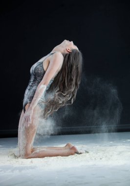 Zarif genç güzel seksi esmer toz bulutu içinde dans uzun saçlı. Toz siyah arka plan üzerine portre genç güzel seksi esmer kadın ile kaplı