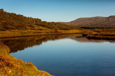 Renkli sonbahar doğası. İzlanda 'ya git. Dağları, gökyüzü ve bulutları olan güzel İzlanda manzarası.