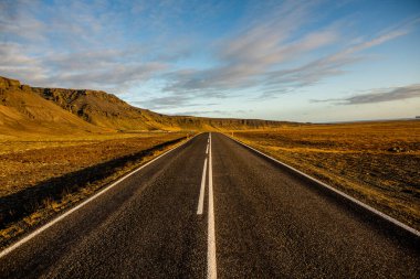 İzlanda 'ya giden yol. Yol ve araba manzaralı ve gün batımlı. Yolculuk konsepti. Araba yolculuğu macerası. Seyahat konsepti. Özgürlük.