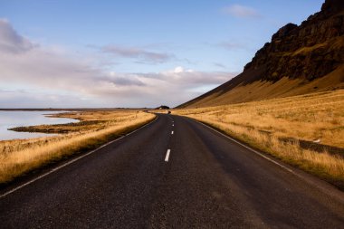 İzlanda 'ya giden yol. Yol ve araba manzaralı ve gün batımlı. Yolculuk konsepti. Araba yolculuğu macerası. Seyahat konsepti. Özgürlük.