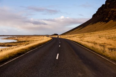 İzlanda 'ya giden yol. Yol ve araba manzaralı ve gün batımlı. Yolculuk konsepti. Araba yolculuğu macerası. Seyahat konsepti. Özgürlük.