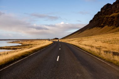 İzlanda 'ya giden yol. Yol ve araba manzaralı ve gün batımlı. Yolculuk konsepti. Araba yolculuğu macerası. Seyahat konsepti. Özgürlük.