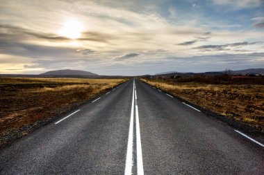 İzlanda 'ya giden yol. Yol ve araba manzaralı ve gün batımlı. Yolculuk konsepti. Araba yolculuğu macerası. Seyahat konsepti. Özgürlük.
