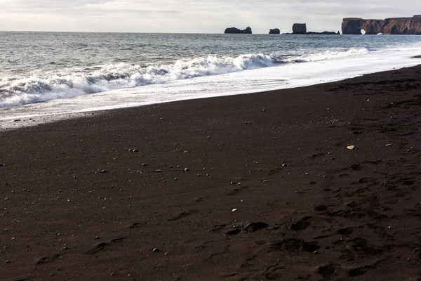 Image of black sand beach near Vik at South Coast of Iceland. White foam on a black lava beach in southern Iceland. Attractions and nature of Iceland.