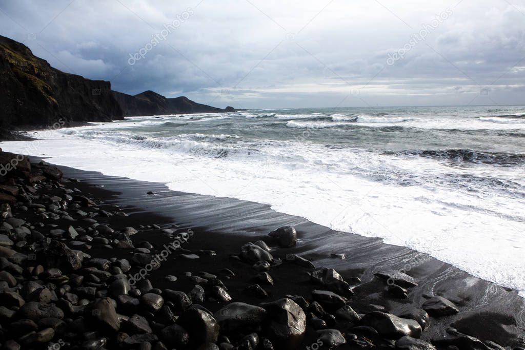 Beautiful coast of the Atlantic ocean with mountains. Waves of the North Atlantic ocean crashing against the beach in iceland after a storm.