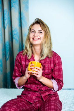 Genç güzel kadın ışık odada kirlenmiş. Rahat kadın pijamalar yatakta yatıyor. Günaydın kavramı - genç kadının uyanmanın mutlu gülümseme ile yüzünde.