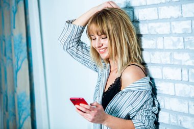 Genç güzel kadın ışık odada kirlenmiş. Rahat kadın pijamalar yatakta yatıyor. Günaydın kavramı - genç kadının uyanmanın mutlu gülümseme ile yüzünde.