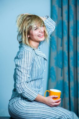 Genç güzel kadın ışık odada kirlenmiş. Rahat kadın pijamalar yatakta yatıyor. Günaydın kavramı - genç kadının uyanmanın mutlu gülümseme ile yüzünde.