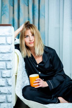 Genç güzel kadın ışık odada kirlenmiş. Rahat kadın pijamalar yatakta yatıyor. Günaydın kavramı - genç kadının uyanmanın mutlu gülümseme ile yüzünde.