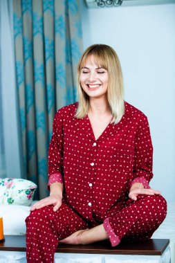 Genç güzel kadın ışık odada kirlenmiş. Rahat kadın pijamalar yatakta yatıyor. Günaydın kavramı - genç kadının uyanmanın mutlu gülümseme ile yüzünde.