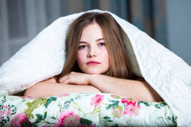 Genç, güzel, beyaz bir kadın aydınlık odada uyanıyor. Rahatlamış bir kadın yatakta uzanıp çay içiyor. Günaydın konsepti. Rus kız..