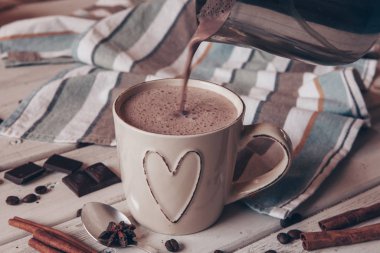 Two cups of hot cocoa with marshmallows and cinnamon sticks on wooden background. Love. Cocoa drink. Valentines day treat ideas.