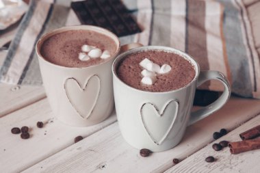 Two cups of hot cocoa with marshmallows and cinnamon sticks on wooden background. Love. Cocoa drink. Valentines day treat ideas.