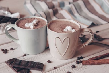 Two cups of hot cocoa with marshmallows and cinnamon sticks on wooden background. Love. Cocoa drink. Valentines day treat ideas.