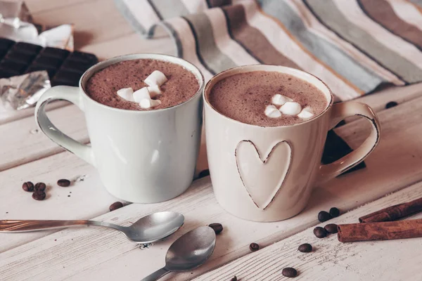 Two cups of hot cocoa with marshmallows and cinnamon sticks on wooden background. Love. Cocoa drink. Valentines day treat ideas.