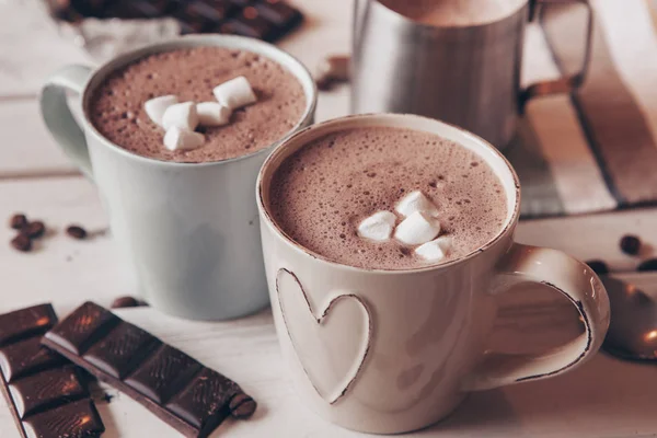 Two cups of hot cocoa with marshmallows and cinnamon sticks on wooden background. Love. Cocoa drink. Valentines day treat ideas.