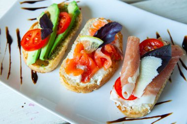 Appetizing bruschetta. Traditional Italian bruschetta. Open sandwich with salmon and vegetables. Delicious healthy food. European cuisine. 
