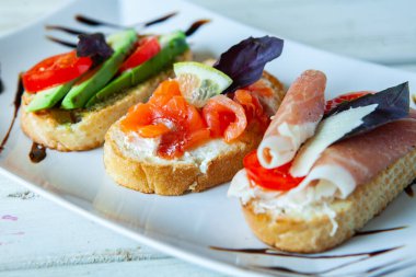 Appetizing bruschetta. Traditional Italian bruschetta. Open sandwich with salmon and vegetables. Delicious healthy food. European cuisine. 