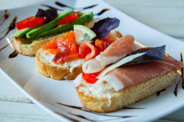 Appetizing bruschetta. Traditional Italian bruschetta. Open sandwich with salmon and vegetables. Delicious healthy food. European cuisine. 