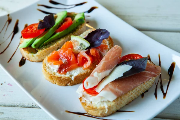Appetizing bruschetta. Traditional Italian bruschetta. Open sandwich with salmon and vegetables. Delicious healthy food. European cuisine. 