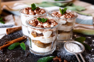Tiramisu cake in glass, classic Italian dessert with mascarpone cream and cocoa. selective focus.