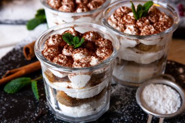 Tiramisu cake in glass, classic Italian dessert with mascarpone cream and cocoa. selective focus.