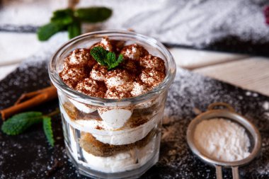 Tiramisu cake in glass, classic Italian dessert with mascarpone cream and cocoa. selective focus.