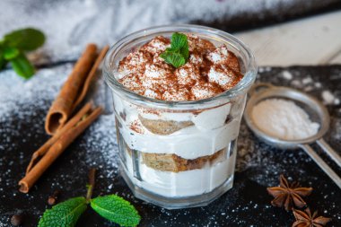 Tiramisu cake in glass, classic Italian dessert with mascarpone cream and cocoa. selective focus.