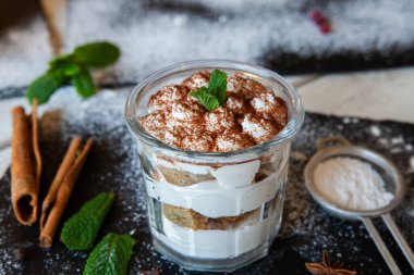 Tiramisu cake in glass, classic Italian dessert with mascarpone cream and cocoa. selective focus.