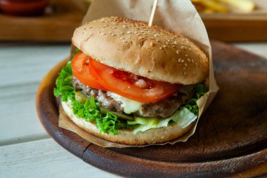 big tasty burger on a wooden table and french fries. Delicious burger with beef, tomato, cheese and lettuce.