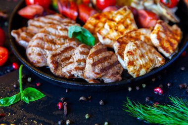 Assorted delicious grilled meat with vegetable. Mixed grilled bbq meat with vegetables. Beef, pork, poultry, sausages, grilled garlic, chili pepper, red tomatoes