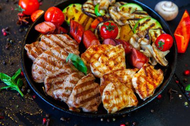 Assorted delicious grilled meat with vegetable. Mixed grilled bbq meat with vegetables. Beef, pork, poultry, sausages, grilled garlic, chili pepper, red tomatoes