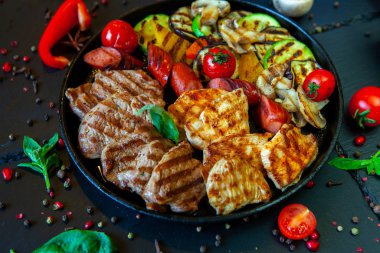 Assorted delicious grilled meat with vegetable. Mixed grilled bbq meat with vegetables. Beef, pork, poultry, sausages, grilled garlic, chili pepper, red tomatoes