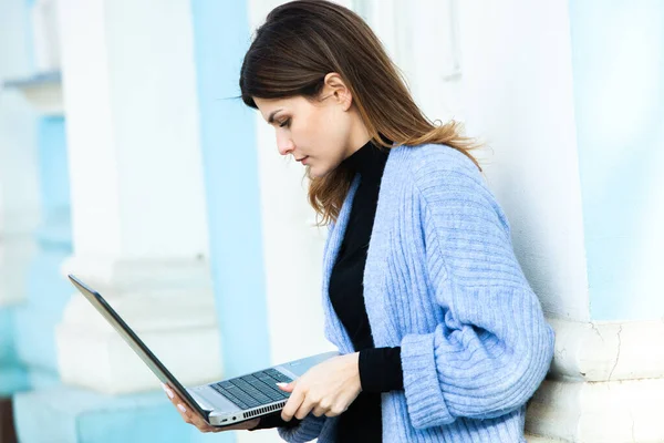 The girl works at the computer in a cafe. Student learning online. Blogger. Young Caucasian female writer keyboarding on laptop. attractive businesswoman using portable computer during a break.