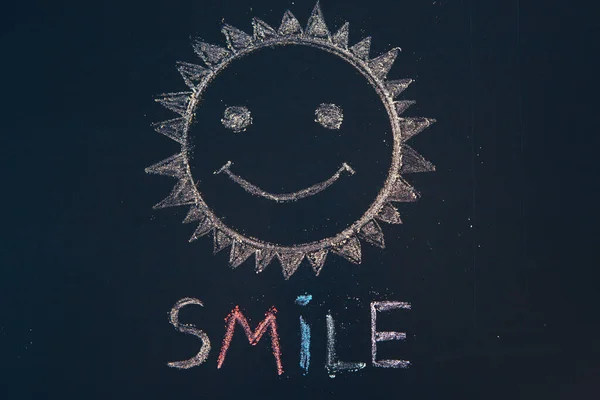 Smile icon painted. Smiling emoticon. SMILE message word on a wooden desk.